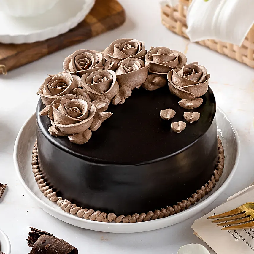 a chocolate cake with mirror glaze and gold roses on top